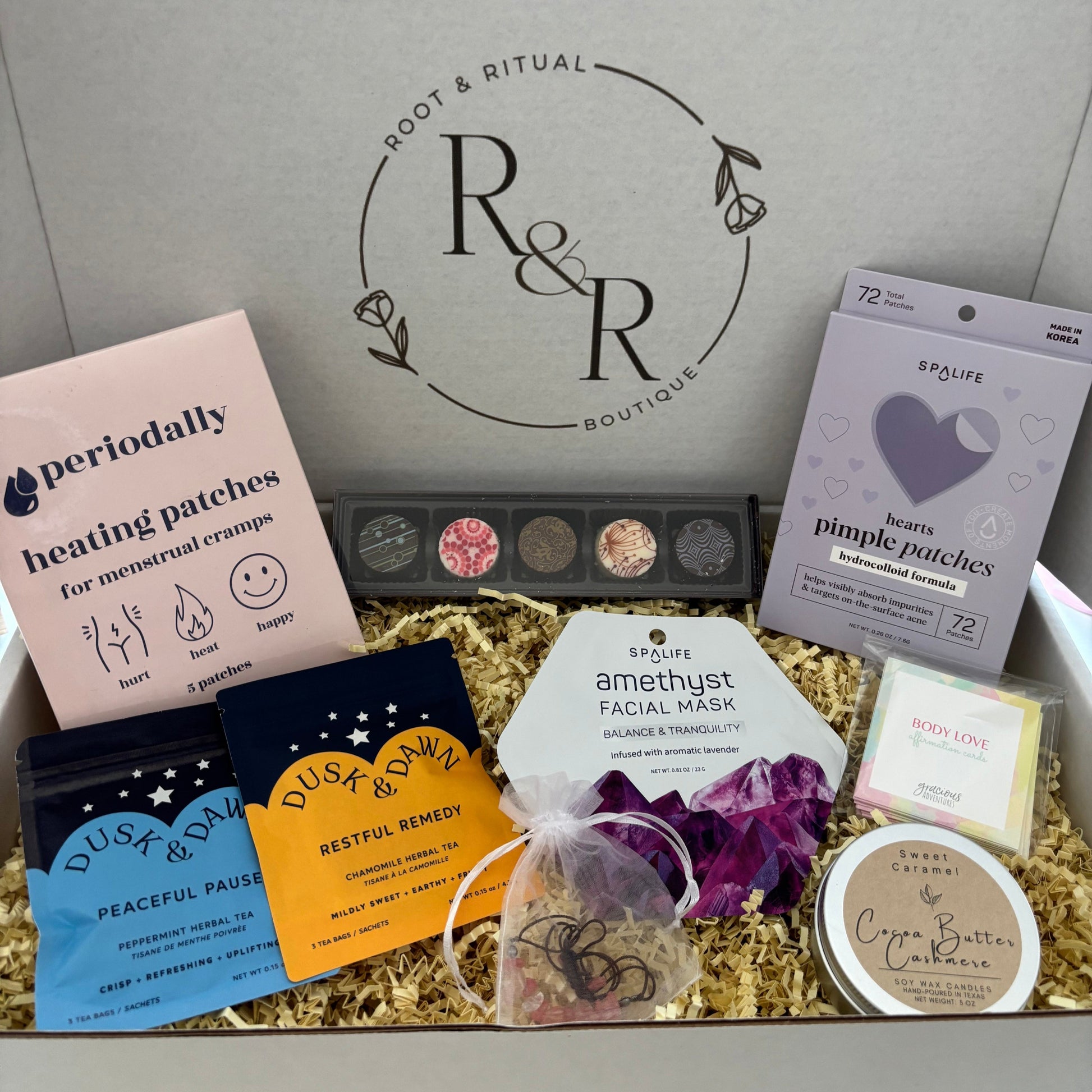 feminine self care gift box for menstrual cycle relief, period cramp relief, feminine energy. Featuring heating patches, pimple patches, korean skincare face mask, affirmation cards, candle, tea blends, chocolate truffles, and crystal energy bracelet