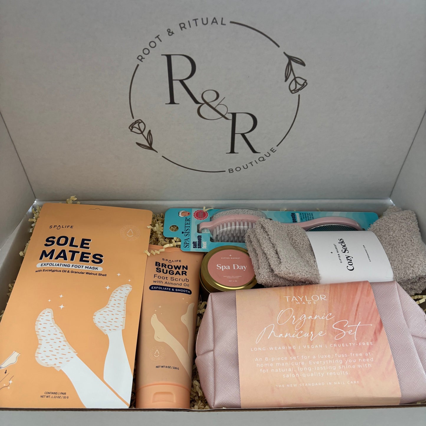 selfcare gift box for nail care including foot mask booties, brown sugar exfoliating foot scrub, spa day soy candle, pedicure foot smoother, cozy socks, organic manicure set (glass nail file, cuticle pusher, hand scrub, base coat, top coat, clear coat, cuticle oil pen, soy nail polish remover, lint free pads, vegan leather rose gold clutch bag)