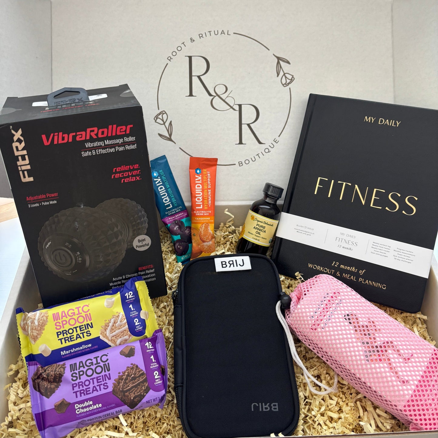 Gift box for fitness and recovery including Daily Fitness Journal for workout tracking and meal planning, pure arnica oil, Brij adjustable wearable weights, Anna Kaci woven resistance bands set, vibrating foam roller, Liquid I.V. drink mixes, Magic Spoon Protein bars, personal training session