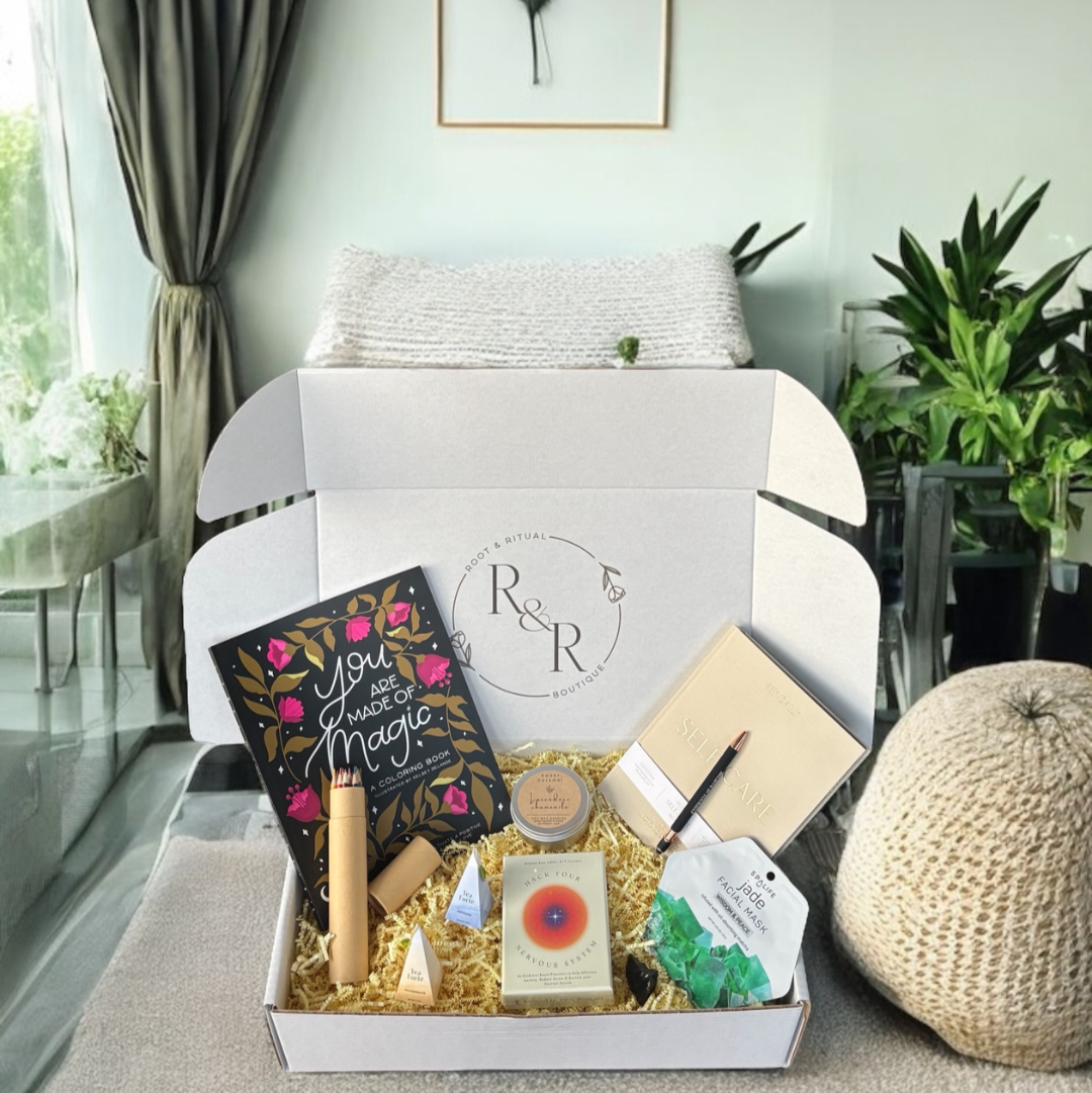 self care gift box for mindfulness and stress relief featuring self care journal, adult coloring book with affirmations, colored pencils, wellness tea, jade and matcha face mask, amethyst crystal, black obsidian crystal, lavender chamomile soy candle, hack your nervous system card deck